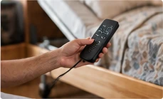 Mão a segurar o comando de uma cama articulada